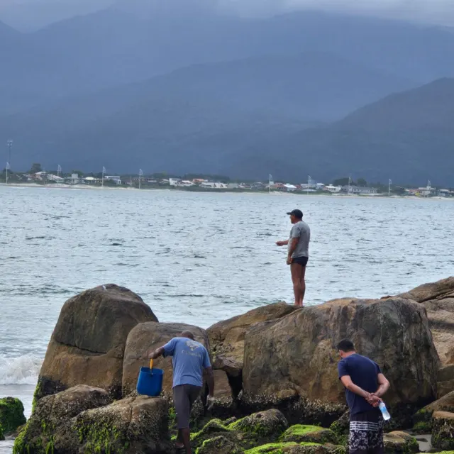 Pescadores nas pedras do costão