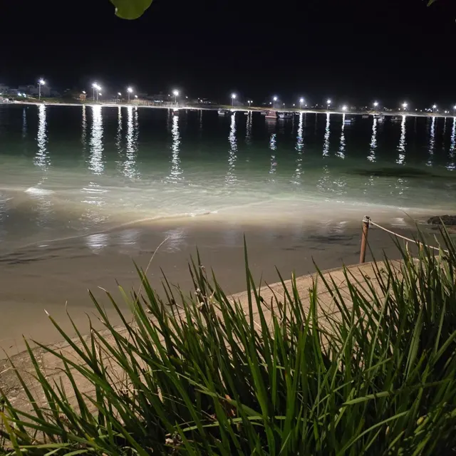 Praia à noite com as luzes da orla